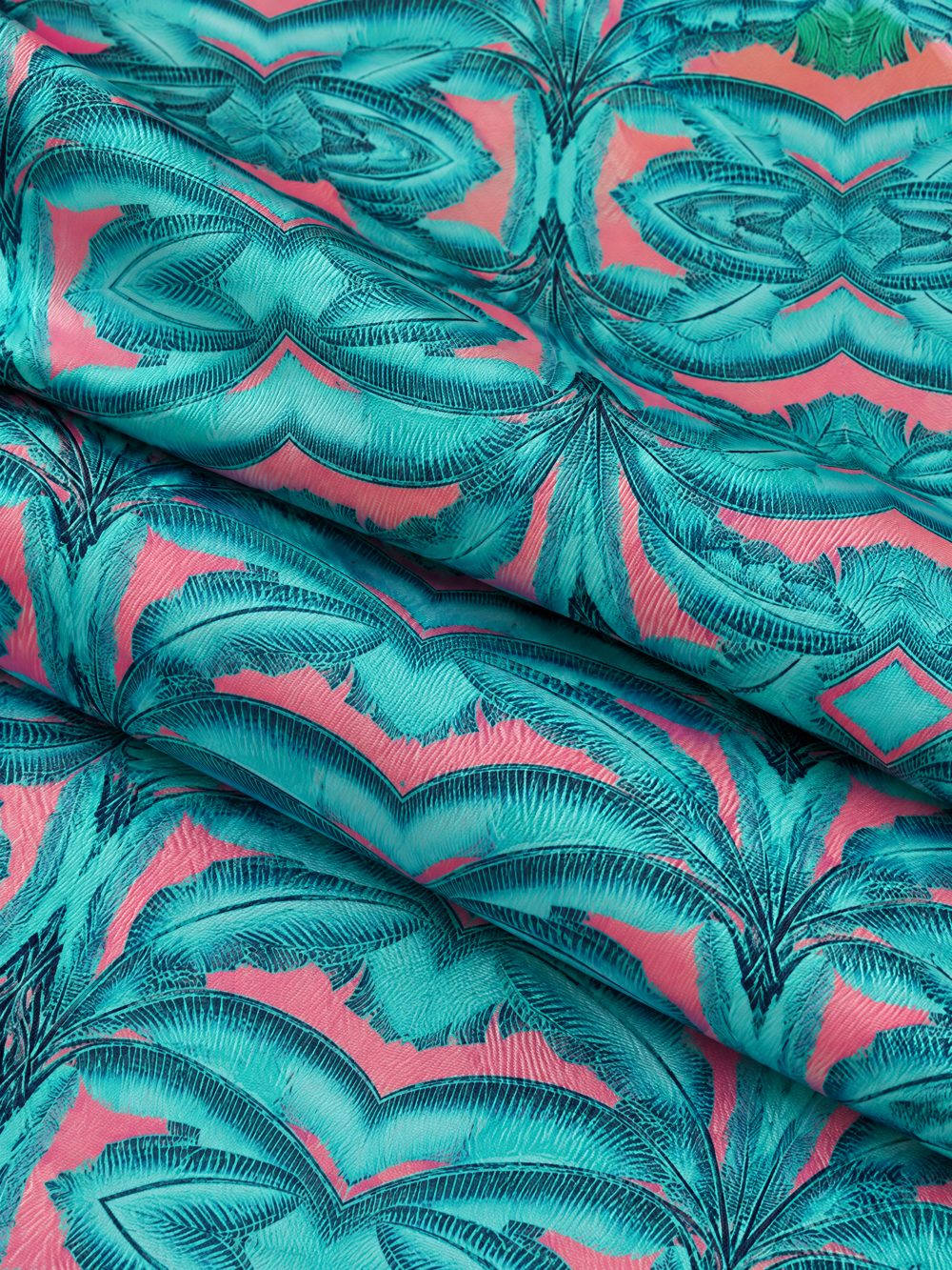 Close-up of Banana Leaves in Jade and Pink printed on folded fabric