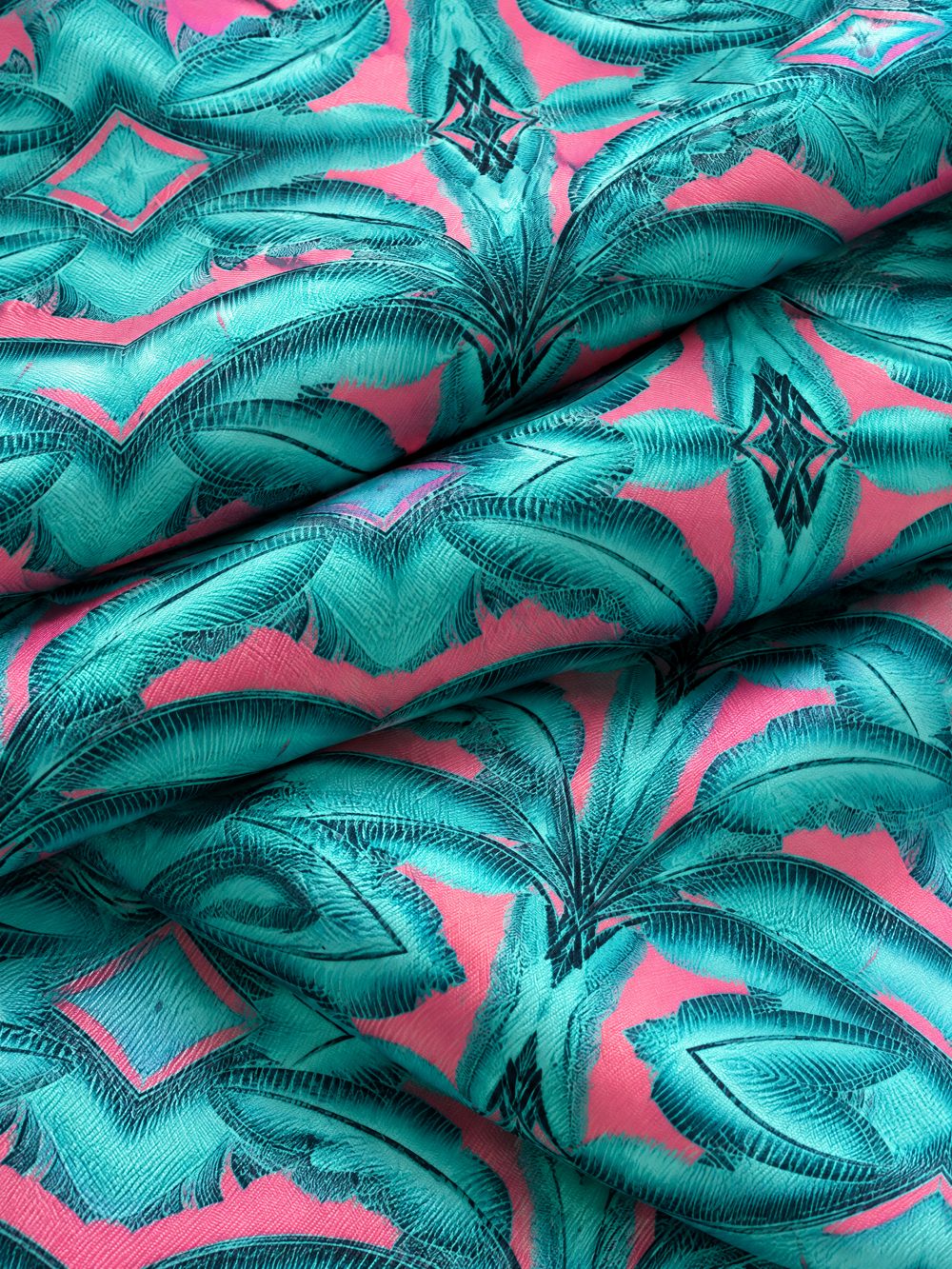 Close-up of Banana Leaves in Jade and Pink printed on folded fabric
