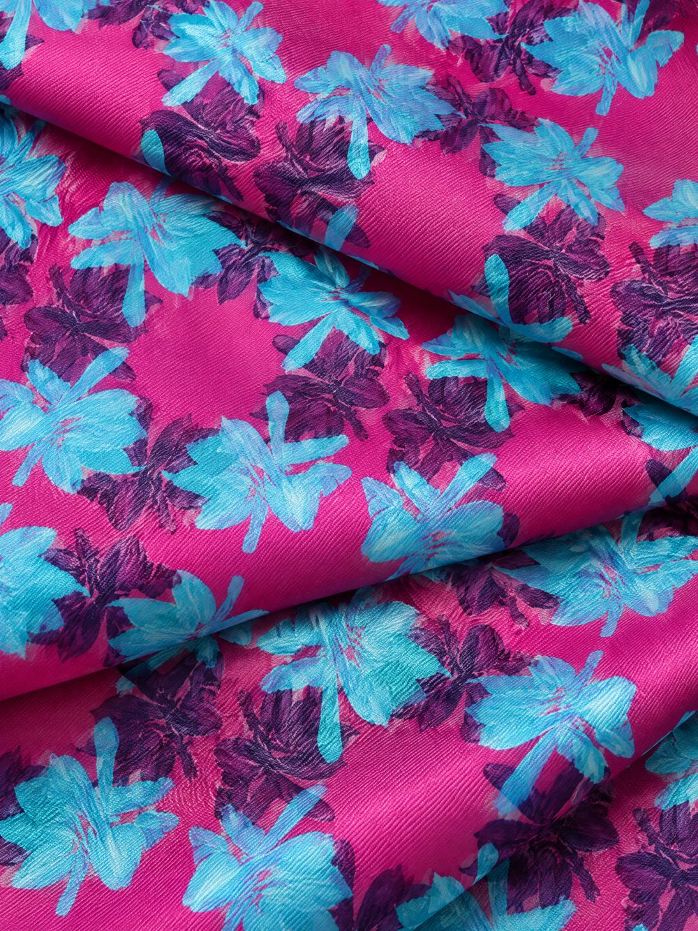 Close-up of Banana Leaves in Magenta and Aqua printed on folded fabric