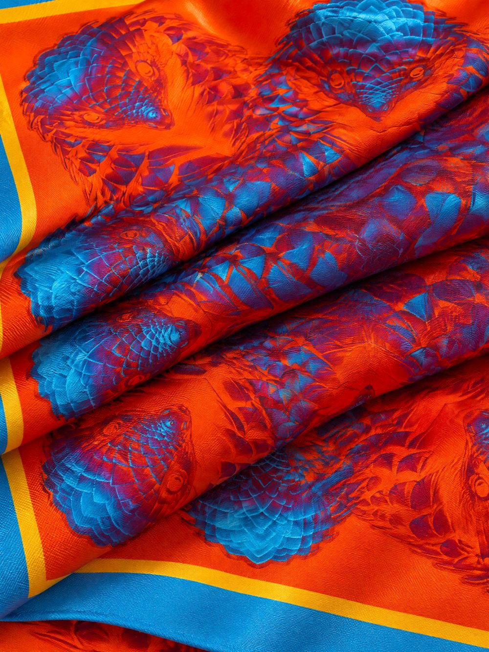 Close-up of The Pangolin's Party Suit printed on folded fabric in orange, magenta and electric blue